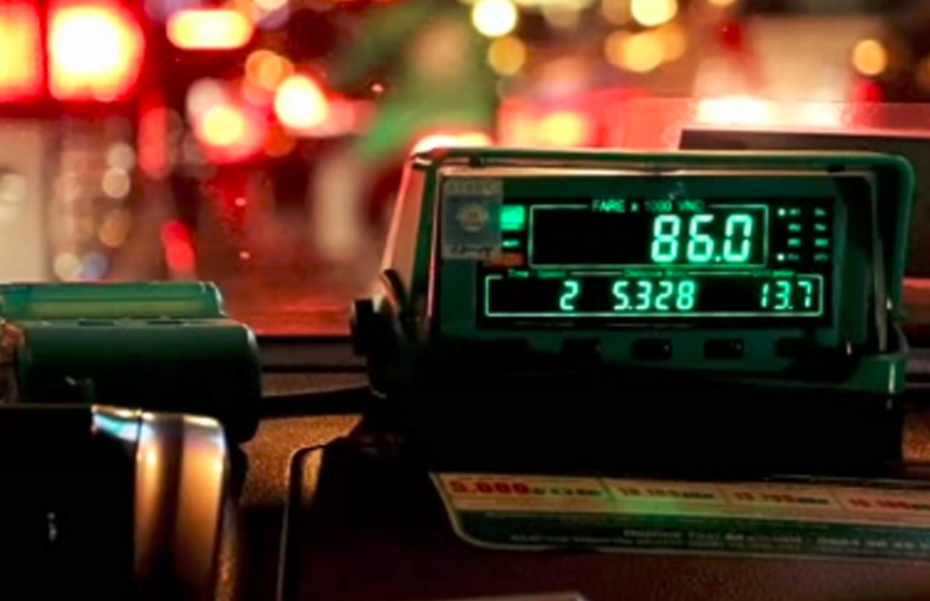 Electronic taxi fare meter at night displaying fare, time, distance, and waiting, with a printed fare card below it